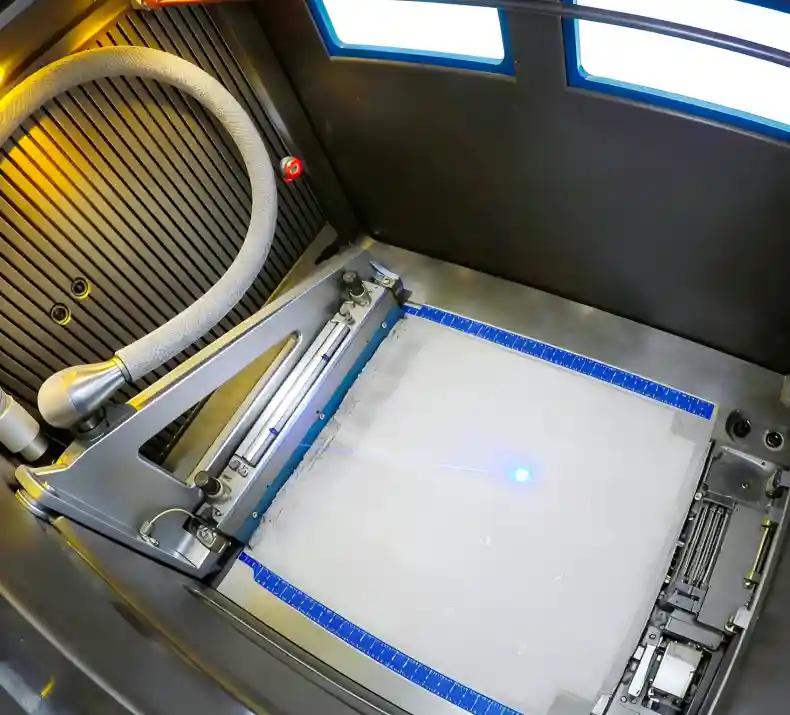 SLS 3D printing machine in operation with laser sintering powder bed